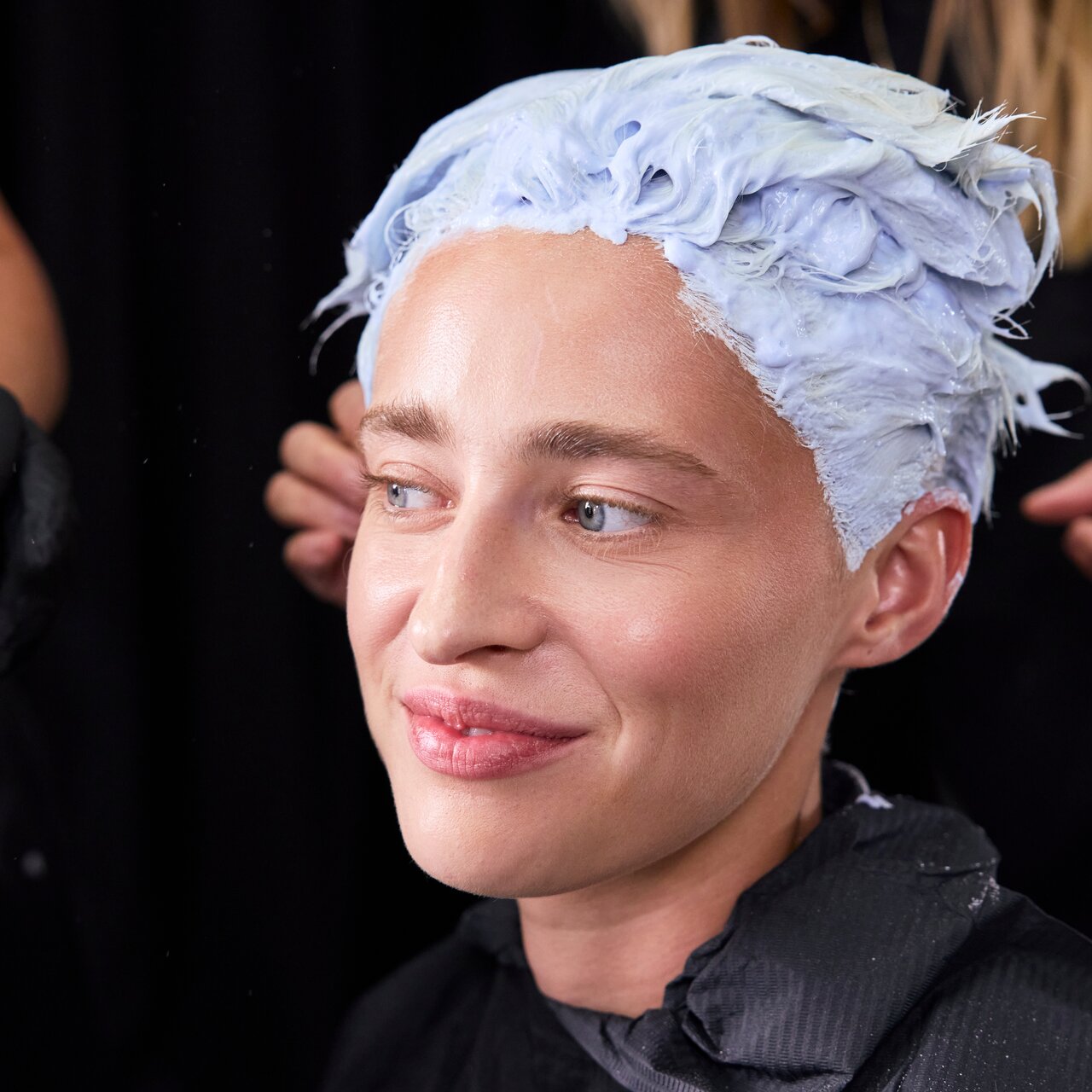 Lächelndes Model während einer professionellen ALCINA Blondierung mit gleichmäßig aufgetragener Blondiermasse.