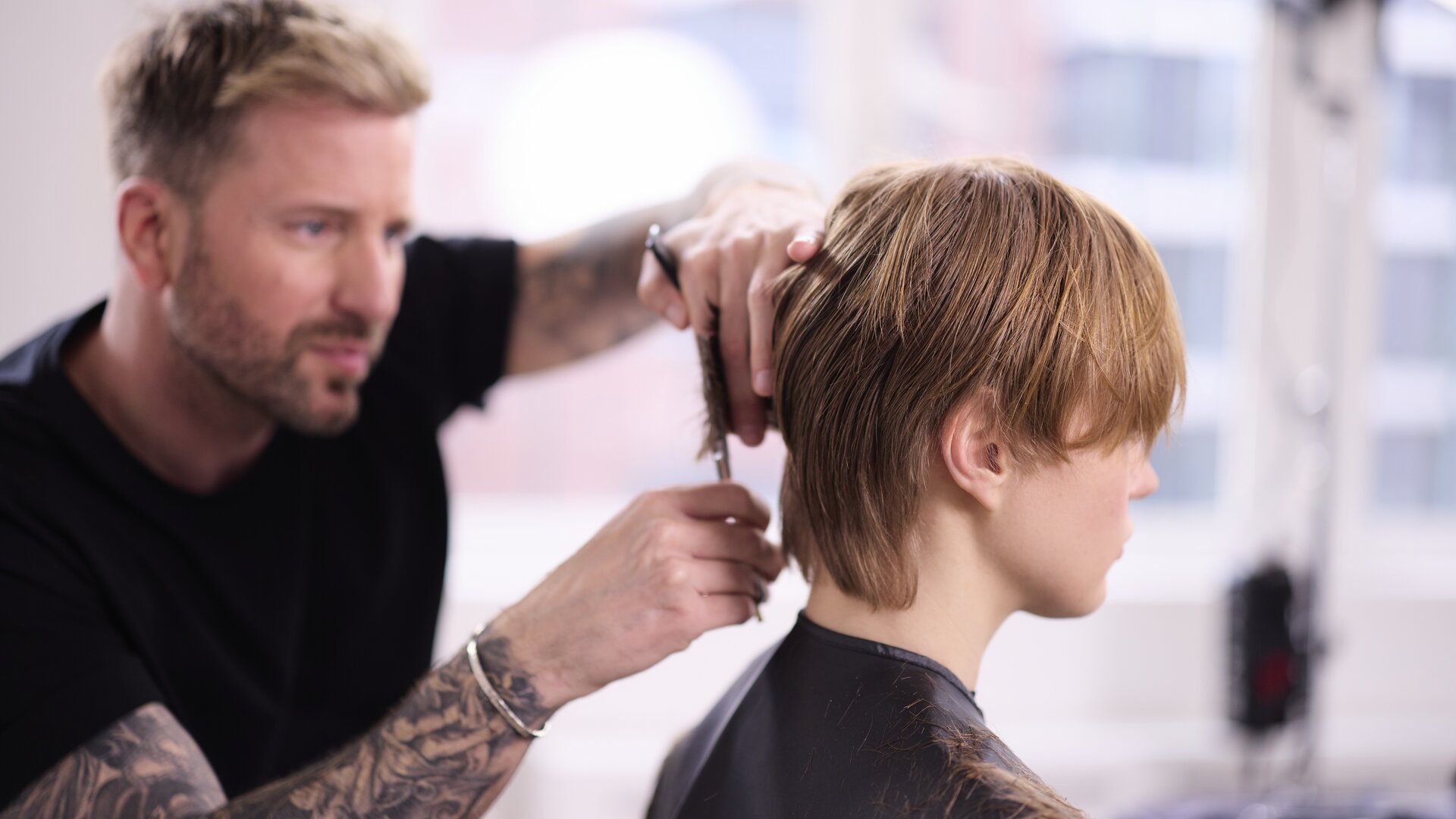 ALCINA Brand Ambassador Robert Mrosek schneidet konzentriert und präzise einen kurzen Haarschnitt bei einem Model.