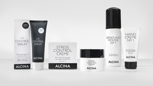 ALCINA Gesichtspflegeprodukte mit UV Control Serum, Stress Control Creme, Reinigungsmousse No 1 und Handcreme No 1 in schwarz-weißem Design, nebeneinander auf hellem Hintergrund arrangiert.