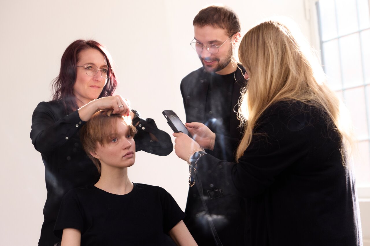 ALCINA Education Seminar, bei dem erfahrene Friseure gemeinsam an einem Model arbeiten und Schnitttechniken demonstrieren, während sie sich über das Styling austauschen.