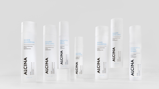 ALCINA Haarpflegeserie mit Basis-Shampoo, Sauerspülung, Feuchtigkeitsspray und weiteren Produkten in weiß-blauem, minimalistischem Design, modern auf heller Fläche arrangiert.