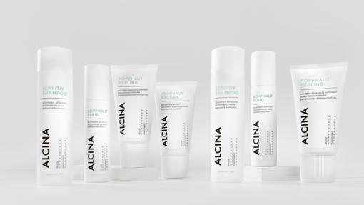 ALCINA Kopfhaut- und Sensitiv-Pflegeserie mit Shampoo, Fluid, Balsam und Peeling in cleanem, weiß-minimalistischem Verpackungsdesign, nebeneinander auf heller Fläche arrangiert.