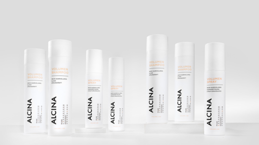 ALCINA Volumen-Haarpflegeserie mit Volumen-Shampoo und Volumen-Spray in weißem, klar strukturiertem Verpackungsdesign, symmetrisch auf heller Fläche arrangiert.